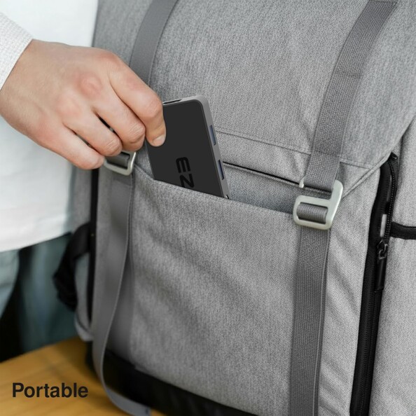 Main rangeant le hub USB-C compact dans la poche d'un sac