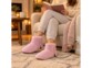 Chaussons roses portés aux pieds, jambes croisées dans un fauteuil