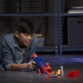 Jeune garçon asiatique couché sur le carrelage noir d'une salle d'archives avec le propulseur Nerf Longshot Smash et ses accessoires