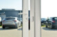 Mise en situation du capteur sans fil placé sur le cadre blanc d'une porte d'une concession automobile avec aimant sur la partie mobile de la porte à côté de la serrure