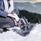 Femme accroupie mettant en place une chaufferette semelle chauffante dans une de ses bottes de ski sur la neige