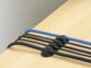 Support noir autocollant en plastique souple collés sur une table en bois clair avec 4 câbles rangés chacun dans une encoche du support