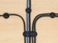Vue du dessus de 4 organiseurs de câble différents guidant 5 câbles vers devant, à droite et à gauche d'une plateforme aspect bois pour ranger les câbles et éviter les emmêlements