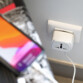 Adaptateur de voyage universel branché à une prise de courant secteur et rechargeant un smartphone par câble de chargement USB blanc