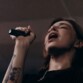 Jeune femme aux cheveux châtains et à l'avant-bras droit tatouée entrain de chanter dans le microphone bluetooth sans fil avec fonction de modification de la voix