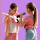 Deux petites filles devant un fond violet dont une jouant de la guitare et une chantant dans le micro du kit karaoké Diablo CGV