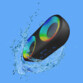 Haut-parleur LED RVB coloris noir plongé dans une flaque d'eau en 3D sur fond bleu illustrant son étanchéité à l'eau