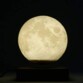 Lune réaliste allumée flottant comme décoration lumineuse au-dessus d'un socle tactile dans l'obscurité