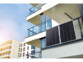 2 panneaux solaires 150 W suspendus au garde-corps d'un balcon d'un immeuble moderne par le biais de leur crochet de suspension