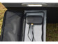 Gros plan sur le régulateur de charge noir contenu dans une des poches d'un pied de support du panneau solaire 100 W, branché à 2 appareils