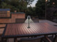 Petite lampe de table d'extérieur placée sur une table en bois d'un salon de jardin du même type sur une terrasse d'un jardin