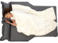 Vue du dessus d'une jeune femme métisse dormant les cheveux attachés sur le lit gonflable pour voiture en étant en débardeur et recouverte d'une couverture blanche