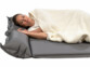 Femme couchée sur le côté sur le matelas gonflable gris anthracite avec la tête posée sur l'un des deux oreillers et un plaid sur son elle