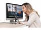 Femme assise à un bureau et parlant devant le micro filaire sur trépied devant un écran d'ordinateur type MacBook allumé sur une plateforme de réunion professionnelle 