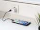 Mise en situation du chargeur rapide Revolt coloris blanc branché à une prise de courant et à un iPhone allumé par câble USB vers Lightning noir sur un meuble de bureau